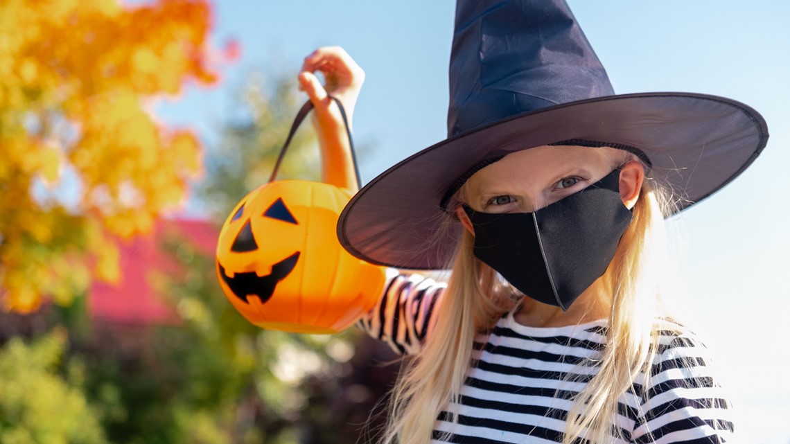 Young girl with plastic pumpkin in hand with mask.