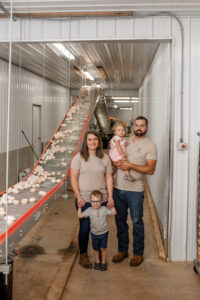 Family standing next to egg conveyer belt